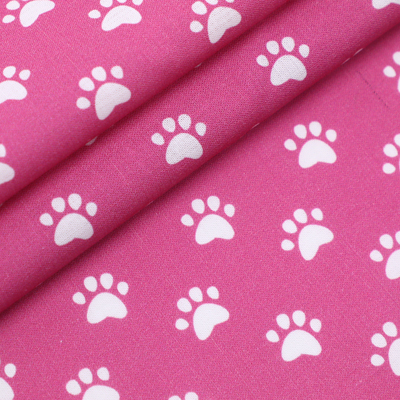 Pink fabric with white paw print pattern, folded to show texture and pattern continuity.