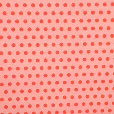 A close-up fabric sample featuring bright red polka dots evenly spaced on a light red background, with the fabric folded to show texture and pattern alignment.