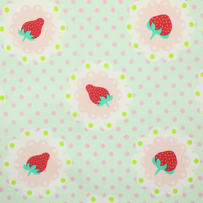 Pale green fabric with pink and green polka dots and strawberry motifs within pink scalloped circles.