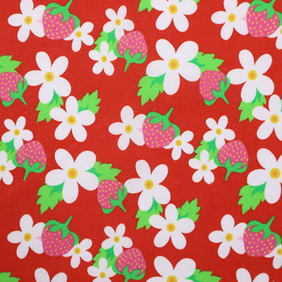 Red fabric with a pattern of white flowers and strawberries displayed flat.