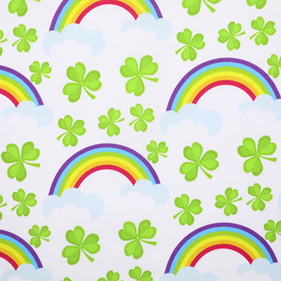 White fabric with a pattern of green clovers and rainbows.