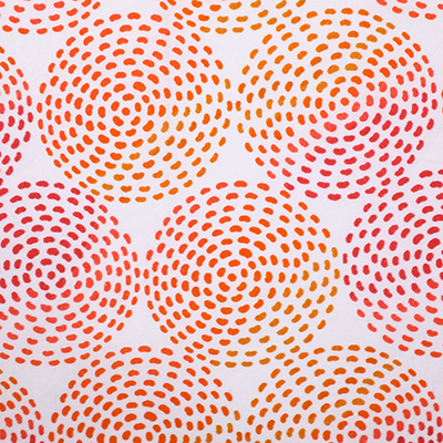 A close-up view of a white fabric with a colorful pattern of circular dotted designs in shades of red, orange, and yellow.