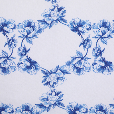 A piece of white fabric with a repeating pattern of blue floral clusters, arranged in a symmetrical and decorative design.